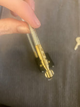 Load image into Gallery viewer, A close up of the gold, metal end of the cable, which gets inserted into the lock.
