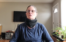 Load image into Gallery viewer, Lisa is wearing a black fleece neck warmer around her neck. It has folds in it, and sits closely around her neck.
