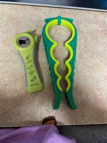 Green jar opener, which has different size cut outs to be squeezed around a jar lid with the handles, sitting beside a green bottle opener that can also open tabs.