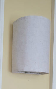 White light sconce on a light yellow wall.