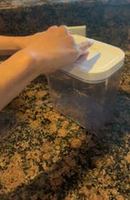Load and play video in Gallery viewer, A container with a white lid and clear container part is sitting on a marble countertop. A person pushes the button on the lid to release the lid, picking up the lid momentarily and then replacing it, before pushing the button again to close the container.
