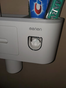 A close up of the side of the holder that has the toothpaste dispenser, where someone inserts their toothbrush into a small opening and pushes the mechanism that releases the toothpaste.