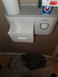 The white drawer is pulled out, with nothing inside. You can see the top of the shelf, with the small cup on one side and the toothpaste dispenser on the other side.
