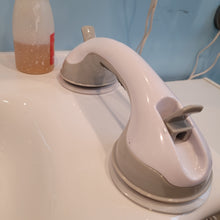 Load image into Gallery viewer, Another view of the grab bar sitting on the white sink, with the clips released. 
