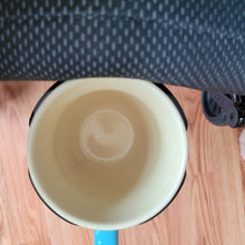 Load image into Gallery viewer, Top down view of a mug in the holder. The handle of the mug sticks out through one of the slits in the holder.
