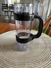 Load image into Gallery viewer, Black adjustable handle is attached to a tall, thin, clear tumbler sitting on a table.
