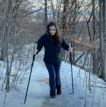 Load image into Gallery viewer, Sarah wears the Kahtoola NANOspikes and uses Montem hiking poles on snowy path in the woods.
