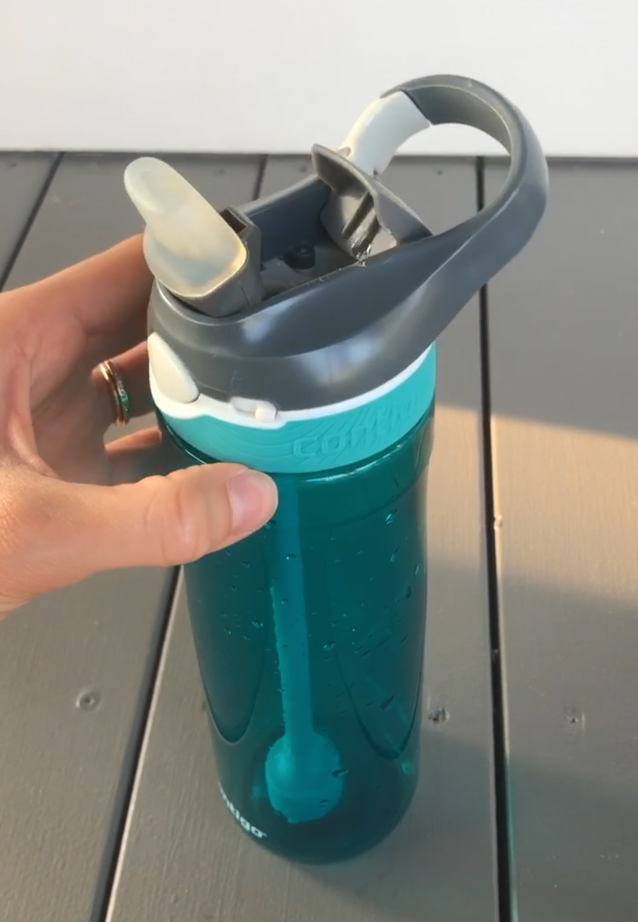 The bottle has a turquoise, see-through base with a gray lid with the spout open. The spout has a clear, thick cover over it. There is a fixed, plastic two-finger 