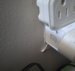 Photo showing Kasa Smart Plug plugged into an outlet with a slight blue light glowing. 