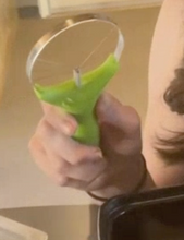 Load image into Gallery viewer, A person is holding the avocado slider, which has a neon green handle and then silver blades in the shape of a pizza.
