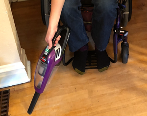 Purple, clear and black Bissell Hand Vacuum with crevice extension piece in action.