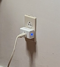 Load image into Gallery viewer, A close-up of the smart plug plugged into a wall. A blue light glows on one side. A cord is plugged into the smart plug.
