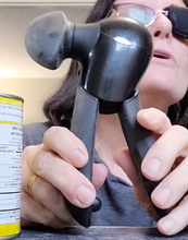 Load image into Gallery viewer, A person is holding a black OXO Good Grips Smooth Edge Can Opener by its handles, pulling them slightly apart. The large turning knob is visible on the left side.  
