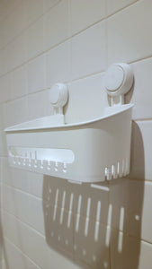 White shower caddy, empty, hanging from two round suction cup attachments 