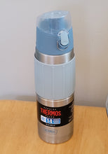 Load image into Gallery viewer, Thermos water bottle on a wood table. It is light blue on top with a stainless steel container and a light blue silicone sleeve with ridges. At the bottom is a black label that says &quot;Genuine Thermos Brand&quot; and 14. 
