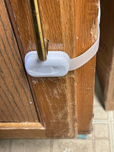 Load image into Gallery viewer, The lock is keeping a single cabinet closed, as one part is fastened to the door of the cabinet and then the other part is stretched around to the side of the cabinet, keeping the lock taught. 
