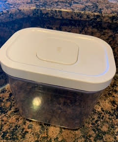Pop container, clear with a white lid, sitting on a marble countertop. The "pop" button on the lid is closed.